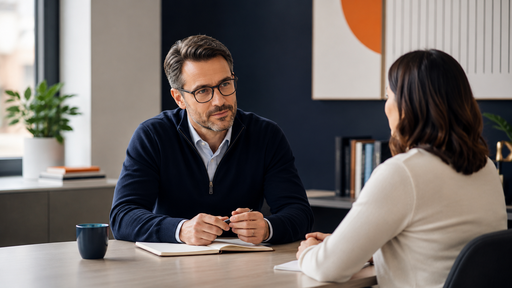 A manager and employee sit across from each other in a calm modern office, beginning a respectful workplace conversation about feedback, trust, and accountability.