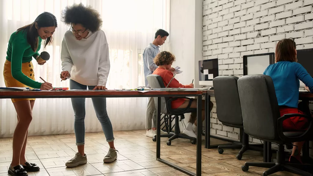 A diverse team collaborating in a strengths-based work environment, demonstrating trust, shared problem-solving, and complementary strengths.