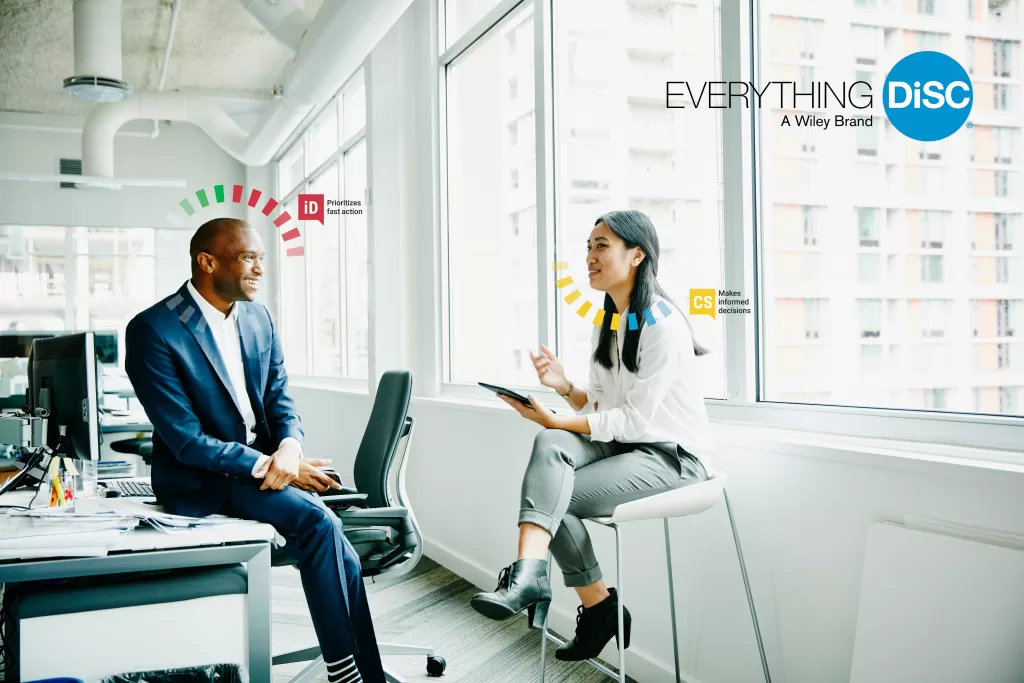 Team members collaborating in an office environment with Everything DiSC® insights displayed.