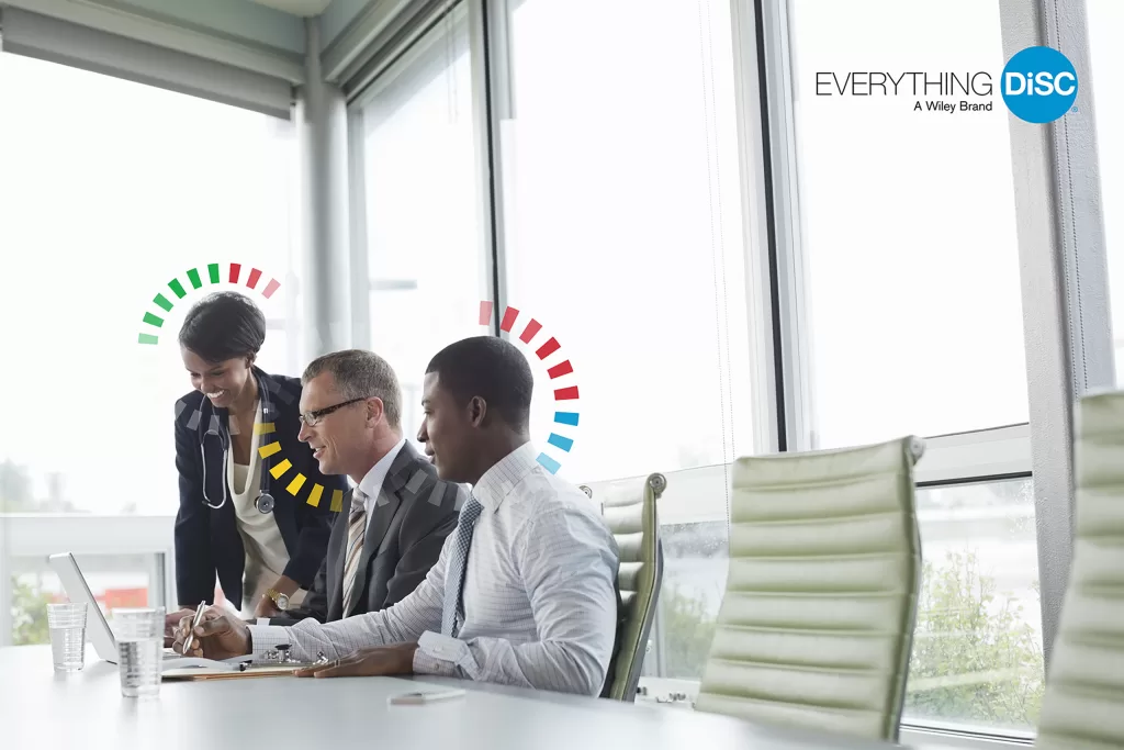 Team collaborating in a modern office with Everything DiSC® style indicators, illustrating how Catalyst supports real-time communication insights.