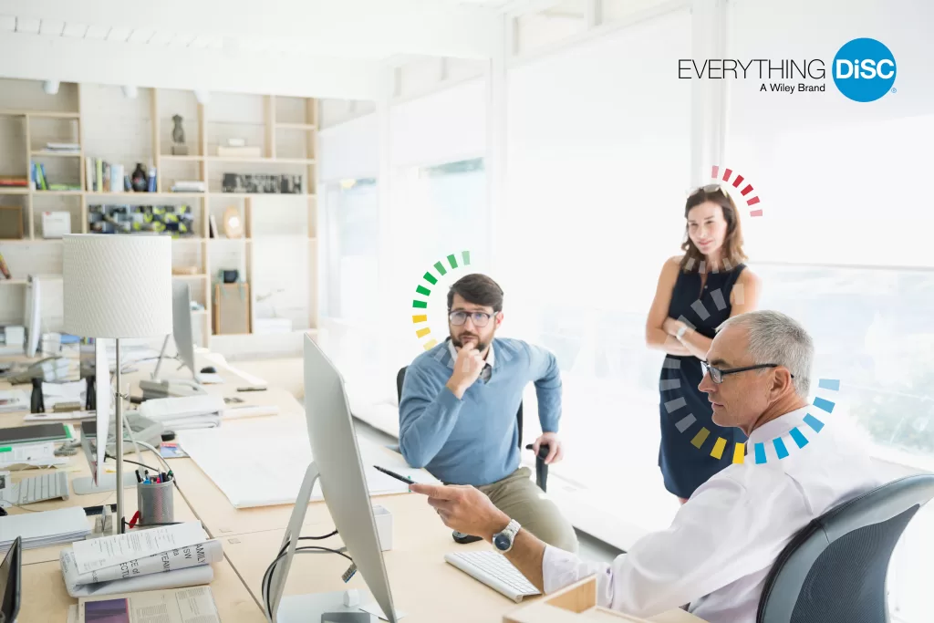 Team collaborating in a modern office with Everything DiSC® behavioral style indicators
